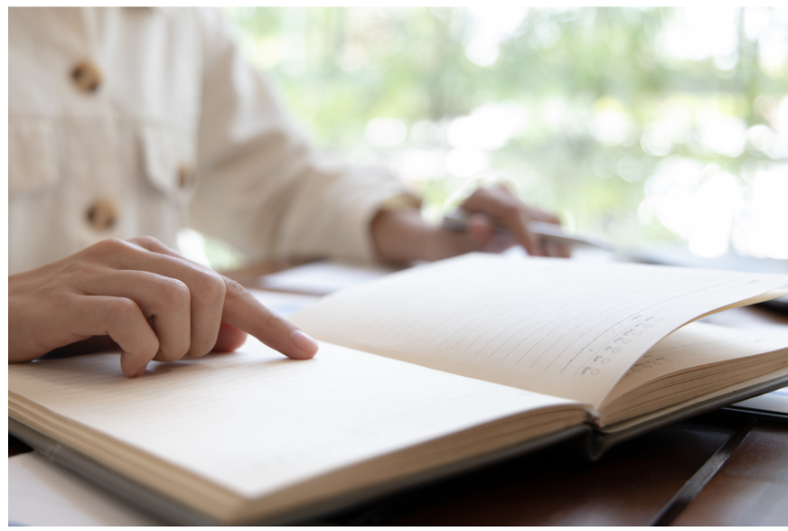 Una persona leyendo un cuaderno, solo las manos son visibles en el cuaderno
